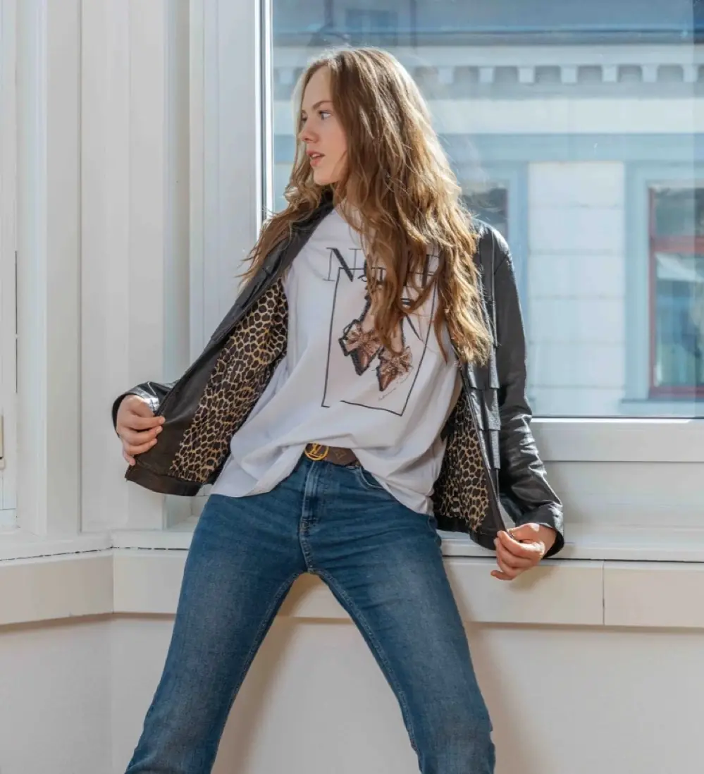 Mädchen in Jeans und Lederjacke am Fenster